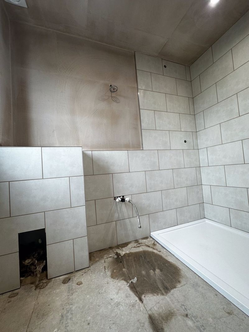 Bathroom mid-tile: boarded walls, part-tiled wall and a new shower tray