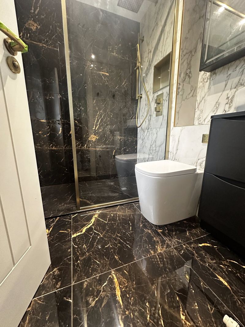 Ensuite tiled in large-format black and gold marble-effect porcelain, with a brass-framed shower screen