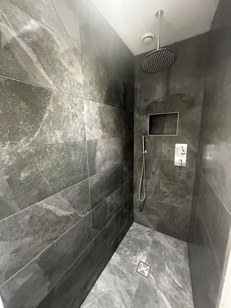 Walk-in wet room with a rainfall shower and recessed niche in slate-grey tiles
